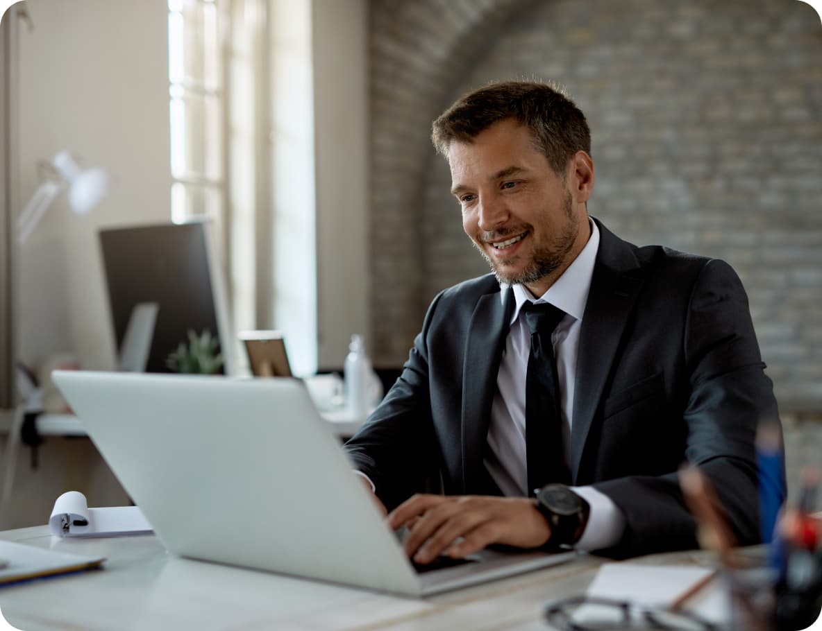 Senior professional smiling while working on a laptop in a modern office